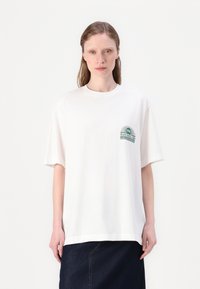 White cotton t-shirt with short sleeves, round neckline, and a green printed graphic on the chest featuring sun and text details.