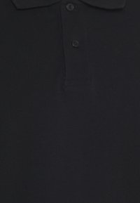 Polo noir doté d'un col classique, d'une patte à deux boutons, fabriqué en tissu tricoté à la texture lisse et aux détails de couture minimaux.