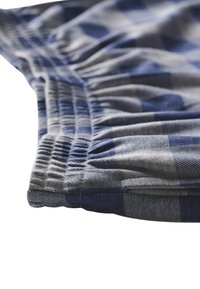 Tessuto scozzese grigio e blu con cintura elastica, caratterizzato da una finitura testurizzata e una caduta morbida, evidenziando cuciture e modelli dettagliati.