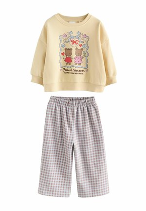 Gelbes Sweatshirt mit Tiergrafik und Text, kombiniert mit karierten hellblauen und pinken Shorts mit elastischem Bund.