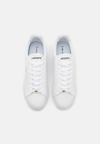 Witte Lacoste sneakers met een glad leren bovenwerk, platte veters en een klein geborduurd logo. Gevoerde voering en gestroomlijnd ontwerp.