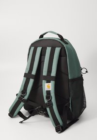 Groene en zwarte rugzak met gevoerde verstelbare schouderbanden, een mesh zijvak en een logo patch aan de voorkant. Stevig ontwerp en materialen.