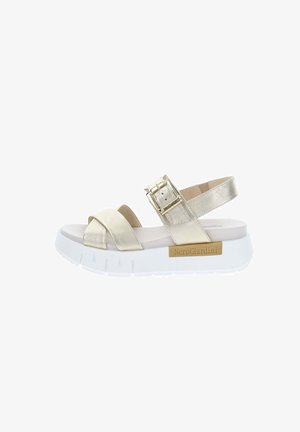 Sandalo beige con suola bianca spessa, ampi cinturini frontali, cinturino regolabile con fibbia alla caviglia e logo NeroGiardini sul lato.
