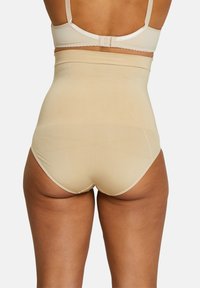 Shapewear a vita alta in colore nude, realizzato in tessuto morbido. Caratterizzato da un design senza cuciture con una vita elasticizzata. Nessun motivo o hardware visibile.