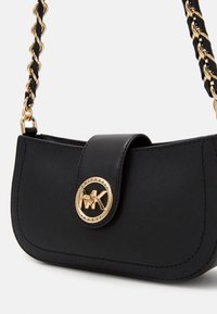 Sort læder håndtaske med en buet form, prydet med en guld logo medaljon, en magnetisk flaplukning og en kædestrop med læderdetaljer.