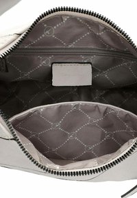 Grijze leren pouch met zwarte rits, met een gevoerde binnenkant in lichtgrijs met een subtiel geometrisch patroon en een klein ritsvakje.