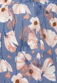 Blumenstoff mit großen Pfirsich- und Rosa-Blumen mit dunklen Zentren auf einem hellblauen Hintergrund. Weiche Textur mit Falten und Taschen-Detail.