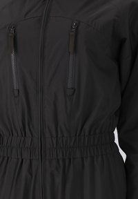 Schwarze Jacke mit einem Reißverschluss vorne und zwei Reißverschlusstaschen. Elastischer Bund für eine anpassbare Passform. Hergestellt aus leichtem, strukturiertem Stoff.