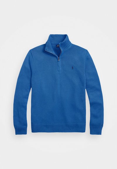 Pullover azul tricotado com um colarinho alto e um zíper de um quarto. Apresenta punhos e bainha canelados, com um pequeno logotipo no peito.
