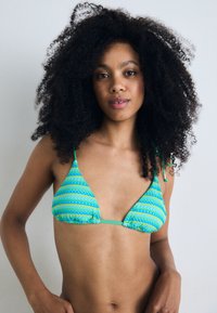 Triangular bikini top in blue and green striped pattern. Made of textured fabric with adjustable ties. Features gathered detailing at edges.