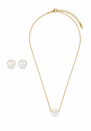 Collier chaîne en or avec un pendentif unique en perle blanche associé à des boucles d'oreilles assorties à perle ronde blanche sur fond blanc.