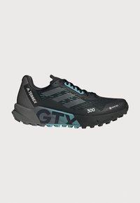 Scarpa da trail running nera con tomaia in rete, dettagli turchesi e suola resistente. Include elementi riflettenti e suola ammortizzata.