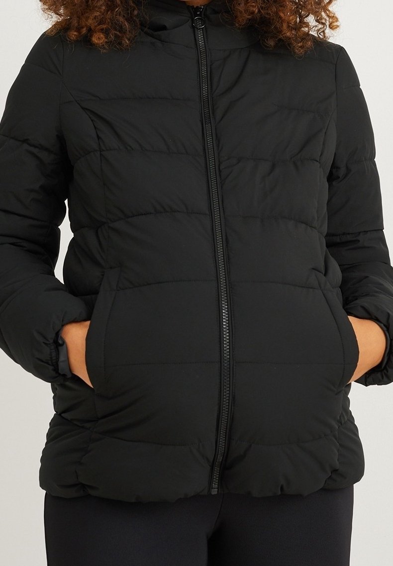 Chaqueta acolchada negra con cierre frontal de cremallera, diseño acolchado y puños elásticos, que cuenta con bolsillos laterales y un cuello subido.