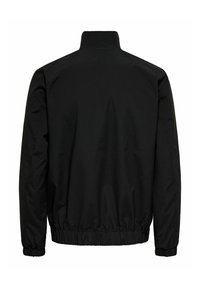 Schwarze Windjacke mit Stehkragen, elastischem Taillenbund und Bündchen. Glatte Textur ohne sichtbare Muster oder Hardware.