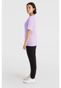 Lavendel T-shirt met korte mouwen, gecombineerd met zwarte broek, met een ontspannen pasvorm, een zachte textuur en een zijsplit aan de zoom.
