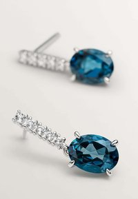 Pendientes de plata de ley con piedras preciosas teal en forma ovalada, que incluyen una fila de piedras transparentes a lo largo del vástago para un detalle y brillo adicionales.