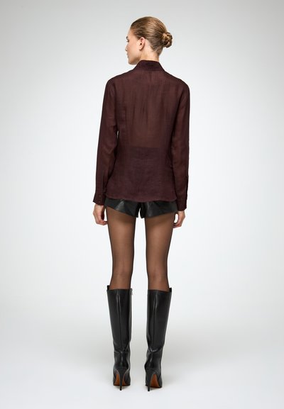 Maroon sheer long-sleeve shirt paired with black leather shorts and knee-high black boots. Smooth texture and fitted design.