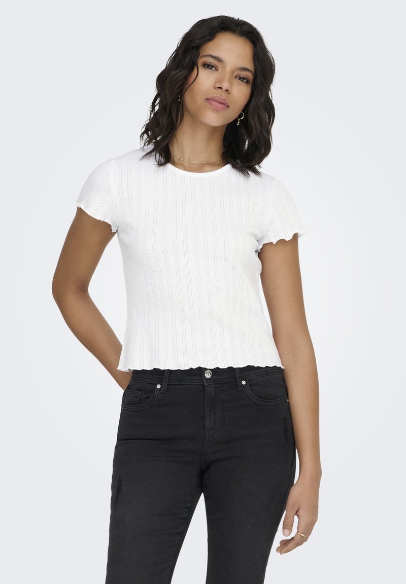 Witte geribbelde gebreide top met geschulpte mouwen, voorzien van een aansluitend silhouet en een ronde halslijn, gecombineerd met zwarte high-waisted jeans.
