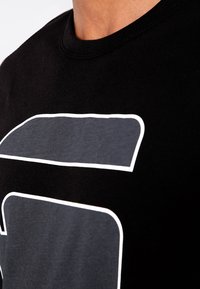 Czarny bawełniany t-shirt z wyraźnym szarym wzorem obramowanym białym kolorem, z klasycznym okrągłym dekoltem i krótkimi rękawami.