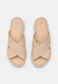 Des sandales à glissière en cuir beige clair présentent un design entrecroisé, une semelle intérieure rembourrée et une semelle extérieure texturée pour une meilleure adhérence. Détails cousus visibles.