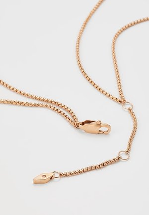 Ketting van roségoud met kreeftenklauwsluiting en klein labeltje op een lichtgrijze achtergrond, met gedetailleerde schakels en bevestigingselementen.