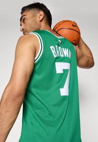 Grøn basketballtrøje med hvide detaljer, der har navnet "BROWN" og nummer "7" bagpå. Struktureret stof, ærmeløs design.