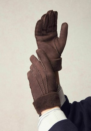 Brown suede gloves with a soft, plush cuff, featuring stitched detailing on the fingers. Durable material and structured design.