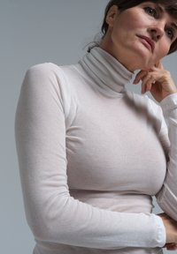 Hvid langærmet polo t-shirt lavet af et blødt, let stof, med en tætsiddende pasform og ribbet krave.