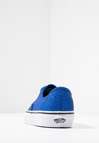 Sneakers Vans blu glitter con suola in gomma bianca e dettagli neri, caratterizzati da un design low-top e un'etichetta sul tallone.