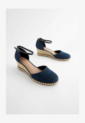 Denimo platformos su apvalia nosimi, juoda kulkšnies dirželiu, šiaudų apvyniotais kulnais ir lygiu tan spalvos vidumi. Savybės - siuvinėjimas aplink pado kraštą.