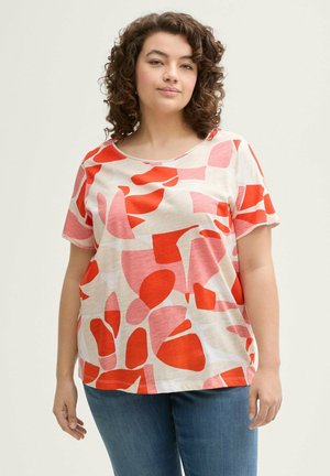 T-shirt à manches courtes de couleur beige clair avec des motifs abstraits irréguliers en rouge et rose. Texture douce, coupe décontractée et décolleté rond.