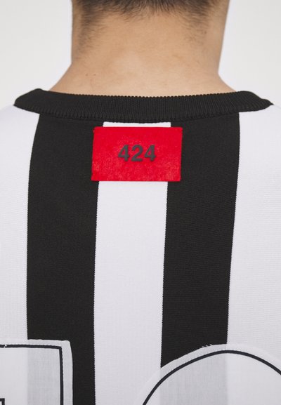 Gestreiftes schwarz-weißes Trikot mit einem roten Patch mit der Nummer "424" auf dem oberen Rücken. Weicher Stoff mit einem gestrickten Kragen.