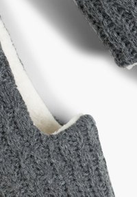 Pantofole grigie lavorate a maglia con foderatura in pelliccia sintetica bianca; presentano un motivo a maglia testurizzato e un design aperto sul retro per una facile calzata.