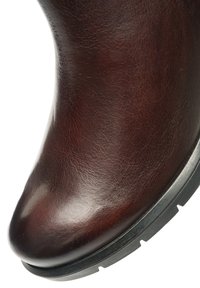 Brown leather ankle boot with a smooth texture, rounded toe, and a black rubber sole featuring distinct traction patterns.