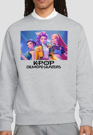 Sweatshirt with colorful digital artwork of three animated female characters and "KPOP Demon Hunters" text below on a gray background.