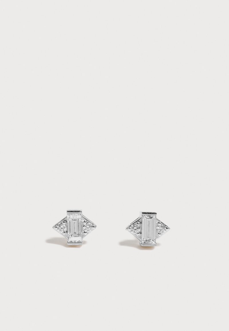Paire de boucles d'oreilles clous ton argent avec des cristaux clairs rectangulaires et triangulaires disposés en un motif géométrique sur fond blanc.