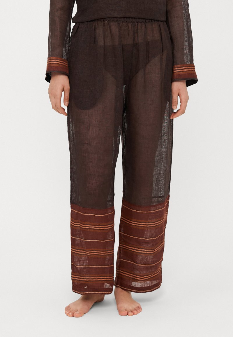 Läbipaistev pruunid püksid elastse vöökohaga, mansettidel julged punaste ja oranžide horisontaalsete triipudega. Kerge kangas.