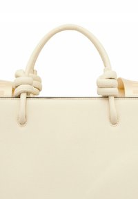 Bolso de mano color crema con una superficie texturizada, que presenta asas anudadas y un diseño minimalista. Detalle de costura notable en los bordes.