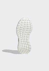 Suola delle scarpe in materiale gommoso bianco, caratterizzata da un motivo testurizzato di scanalature e creste per una migliore presa e aderenza.