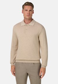 Beige neulepikeepaita, jossa on kaulus, kolmen napin lista, resorireunat hihansuissa ja helmassa. Pehmeä pinta ja vartalonmyötäinen siluetti.