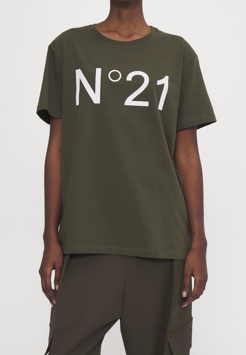 Camiseta de algodón verde oliva con mangas cortas y cuello redondo, con un gran texto estampado en blanco "N°21" en el frente. Diseño de corte recto.