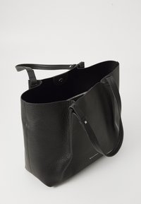 Schwarze strukturierte Leder-Tote mit zwei Schulterriemen und einem Magnetverschluss, teilweise geöffnet, um ein Reißverschluss-Innenfach zu zeigen.