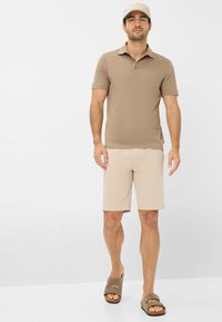 Polo shirt beige, pantaloni corti beige chiaro e sandali marroni. Maniche corte, colletto e vestibilità comoda. Design semplice senza motivi o accenti.