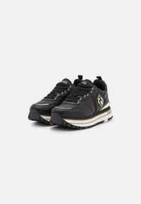 Scarpe da ginnastica nere con tomaia sintetica, accenti dorati, punta rotonda, suola spessa bianca con strisce dorate e battistrada in gomma testurizzata.