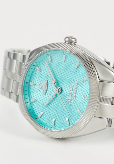 Roestvrijstalen horloge met een gemarmerde turquoise wijzerplaat, zilveren uurmarkeringen en wijzers. Heeft een gestructureerde bezel en een schakelarmband.