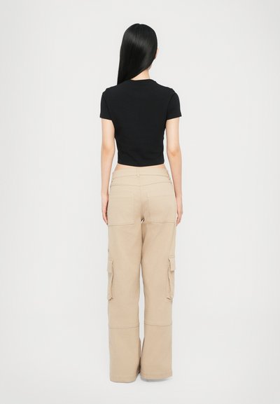 Black short-sleeve top paired with beige cargo pants. The pants feature side pockets and a loose fit, made from a sturdy fabric.