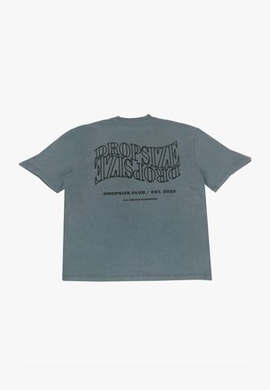 Šedé bavlnené tričko so silným čiernym typografickým dizajnom; text "DROPSIZE CLUB / EST. 2020" je vytlačený v rôznych orientáciách na zadnej strane.