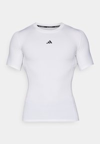 Vitt kortärmat idrottströja med en åtsittande design. Tillverkad av ett slätt tyg med svart Adidas-logotyp på bröstet och en kontrasterande krage.