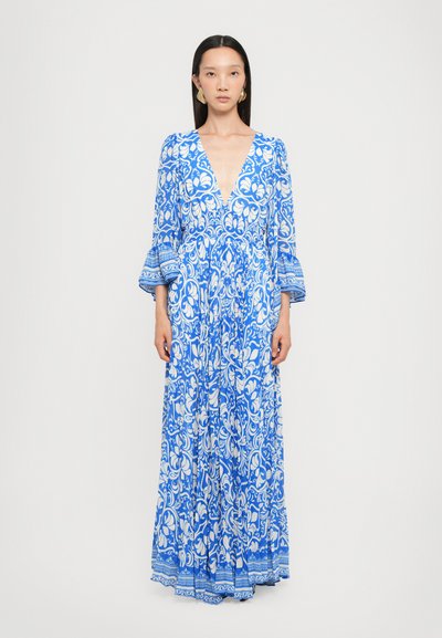 Maxi dress with a deep V-neck, blue and white floral pattern, long bell sleeves, and a flowing, textured fabric. Detailed hem accents.