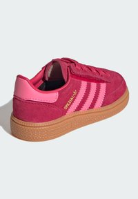 Röda mockaskor med rosa läderdetaljer, tre rosa ränder och en strukturerad gummisula. Har "SPEZIAL" i guld på sidan.